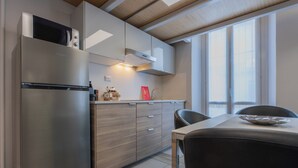 Una cocina moderna con un refrigerador de acero inoxidable, armarios de madera y un comedor con mesa y sillas.