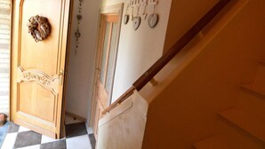A staircase with a wooden handrail, a door with a decorative wreath, and a wall with a 'WELCOME' sign and heart-shaped decorations. - Cottage Oree des bois in Paliseul with garden (Paliseul)