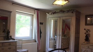 A bedroom with a bed, a dresser, a chair, a wardrobe, and a window with curtains. - Cottage Oree des bois in Paliseul with garden (Paliseul)