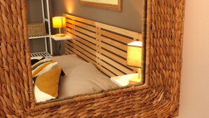 Ein Schlafzimmer mit einem Holz-Kopfteil, zwei Nachttischlampen, einem Bett mit beigem und weißem Kissen und einem gewebten Korb auf dem Nachttisch.