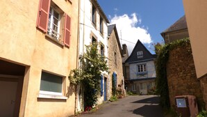 Eine enge Straße gesäumt von traditionellen Gebäuden, mit Steinwänden und Holzläden.