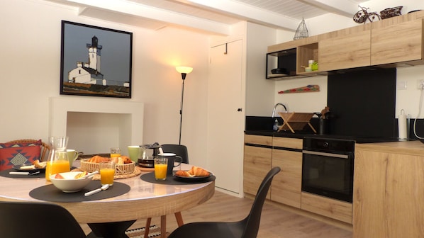 A dining area with a round table set for breakfast, including croissants, juice, and a coffee maker.
