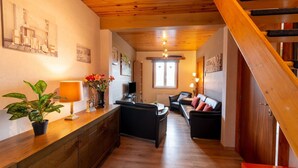 A wooden staircase leading to a living area with a sofa, a coffee table, and a potted plant. - Cozy Family Cottage in Érezée (Erezée)