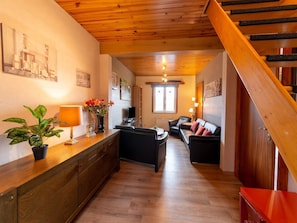 A wooden staircase leading to a living area with a sofa, a coffee table, and a potted plant. - Cozy Family Cottage in Érezée (Erezée)