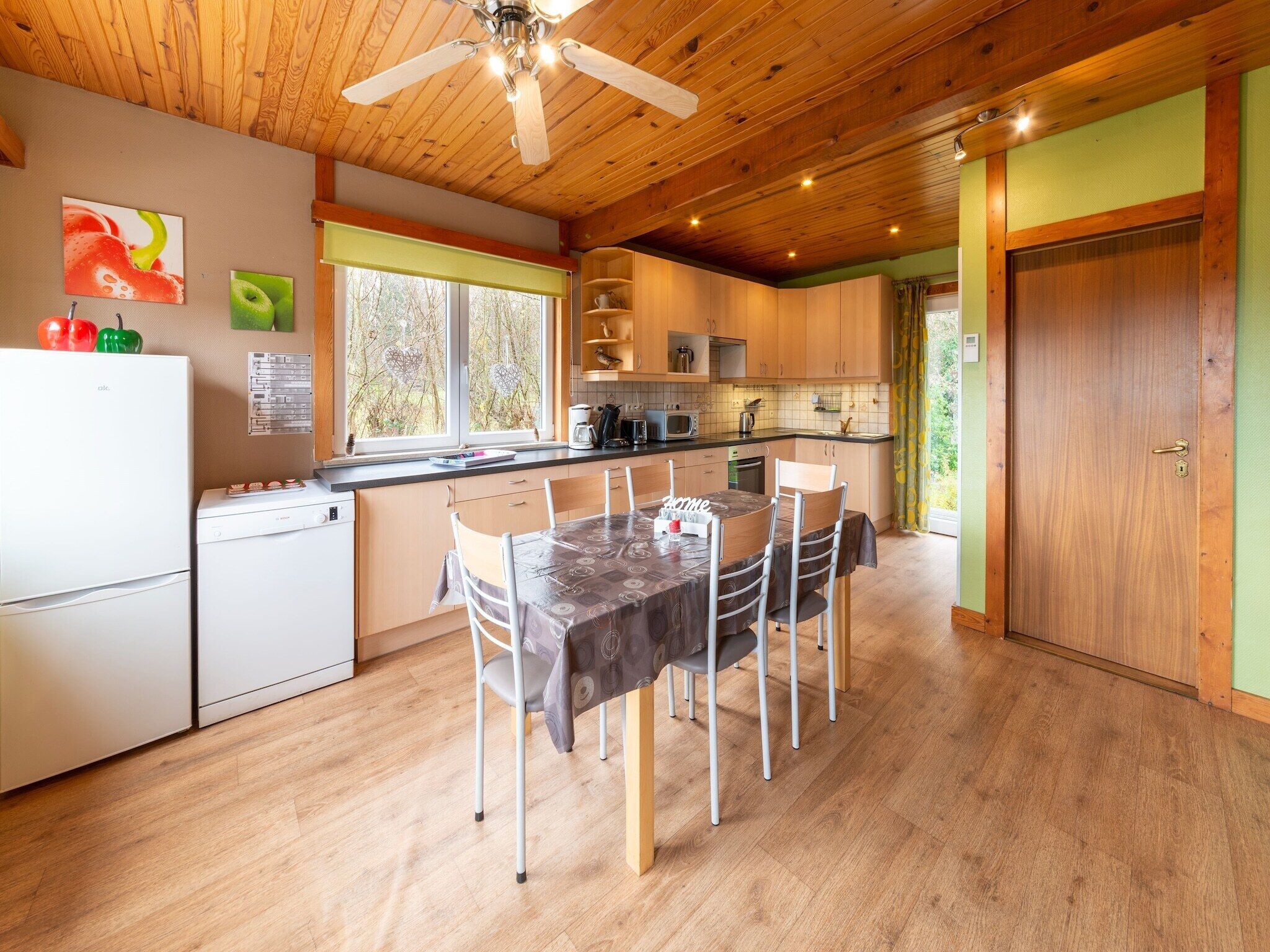 Een keuken met houten kastjes, een eettafel en een plafondventilator.
