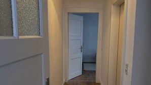 A hallway with wooden flooring, white walls, and a door leading to a room. - Coesfeld outskirts - Quiet apartment for 2 persons, close to town and nature (Coesfeld)
