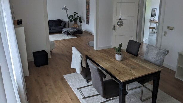 A modern living space with a dining area, a sofa, a coffee table, and a potted plant. - Coesfeld outskirts - Quiet apartment for 2 persons, close to town and nature (Coesfeld)