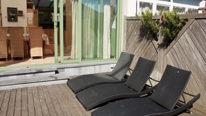 Eine Terrasse mit zwei Liegestühlen und einem Holzzaun.