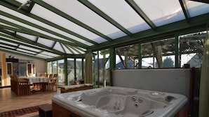 Ein Whirlpool in einem Wintergarten mit Essbereich und Küche.