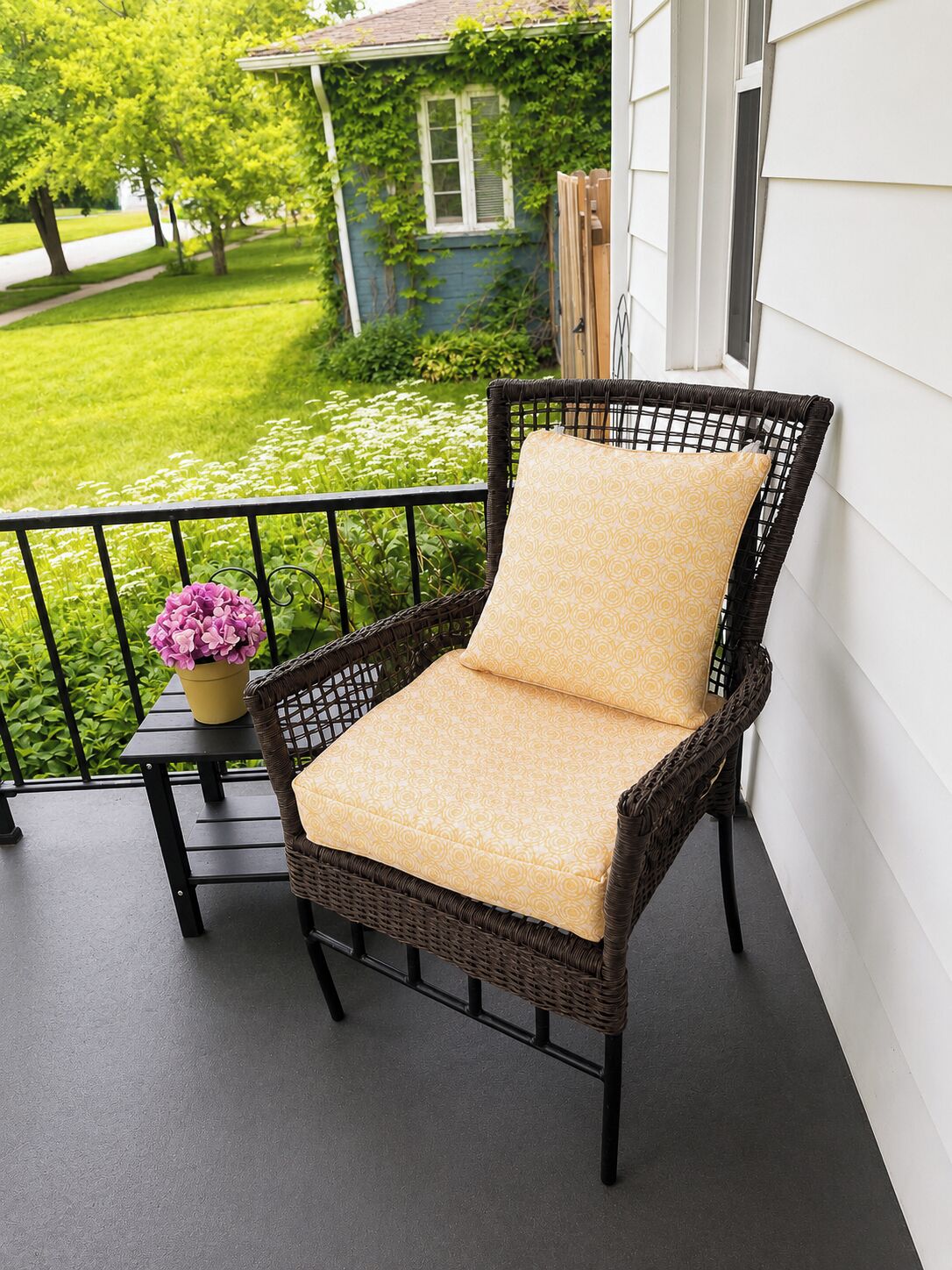 A wicker chair with a cushion on a balcony with a railing.