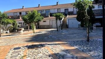 A courtyard with a mosaic floor, a building with a tiled roof, and a staircase leading to a garage.