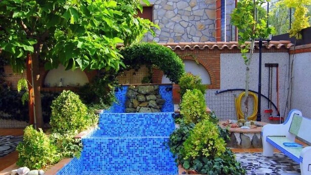 A patio with a mosaic pool, a white chair, and a table with a yellow hose. - Exclusivo Loft en Zaragoza-2 (Movera)
