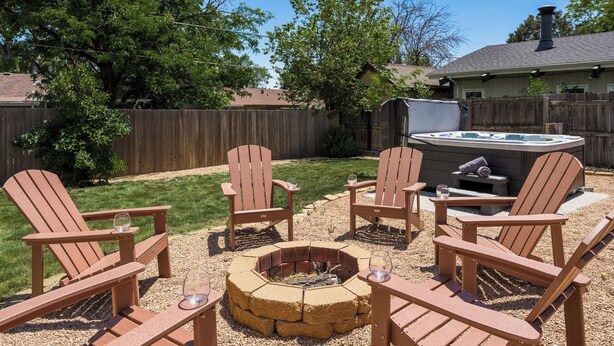 Un jardin avec un foyer, des fauteuils Adirondack et un jacuzzi.