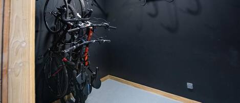A room with a bike rack holding two bicycles and a wall-mounted hook.