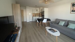 A modern living room with a sofa, a dining table, and a TV.