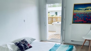 A bedroom with a bed, a window, and a view of the outside.