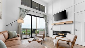 Un salon moderne avec un canapé, des fauteuils, une cheminée et un téléviseur fixé au mur.