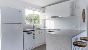 Una cocina moderna con armarios blancos, encimera de granito y ventana que proporciona luz natural.