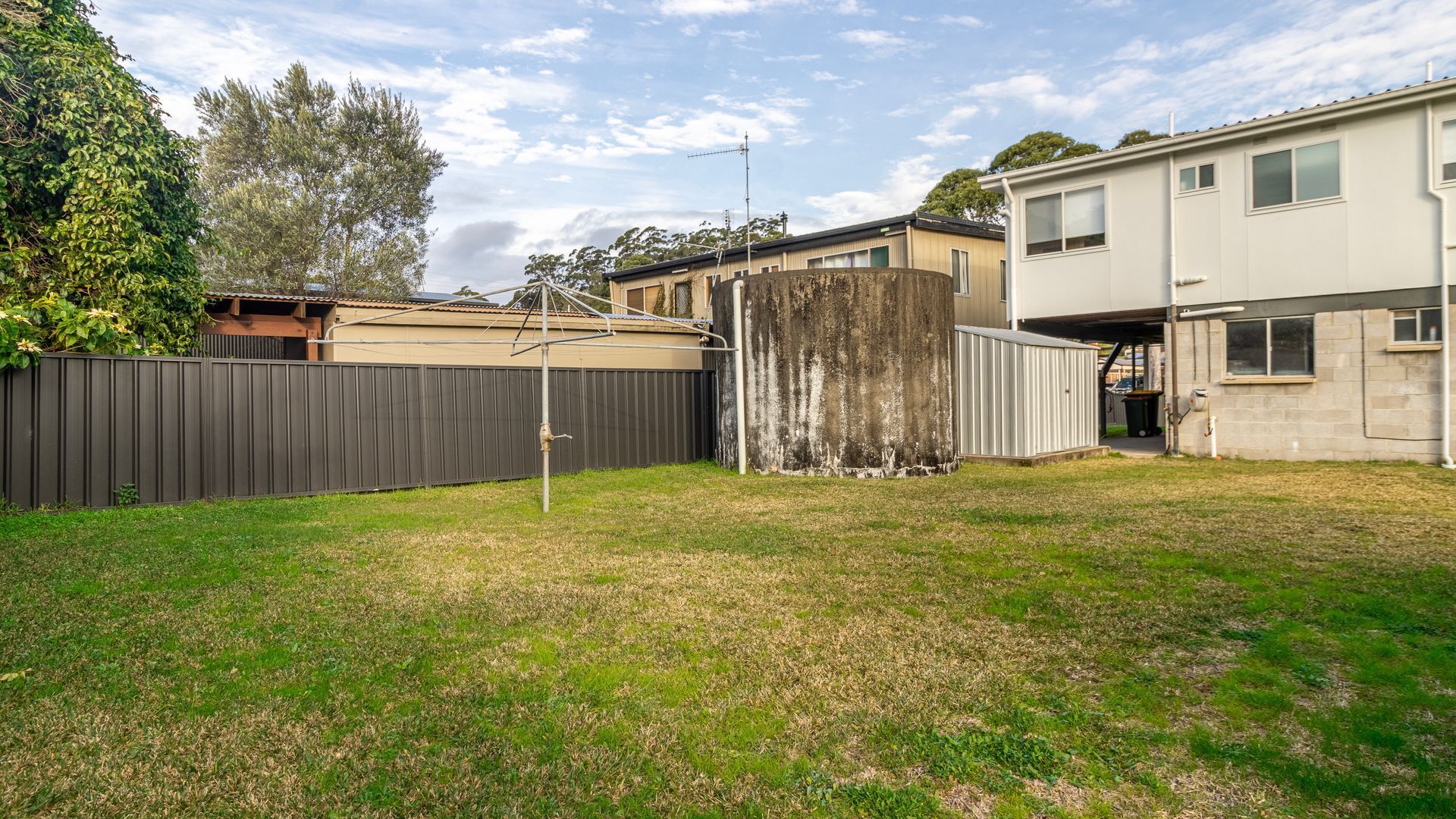 A residential backyard with a fenced area, a utility pole, and a detached garage.