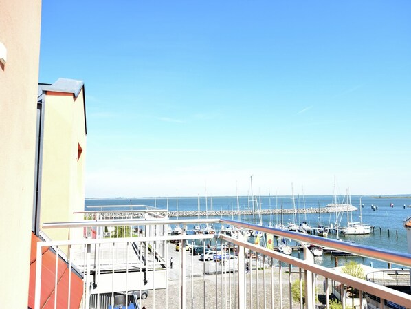 A marina with boats docked, a clear sky, and a building with a balcony overlooking the water. - Exklusive Panoramawohnung in Barth (Barth)