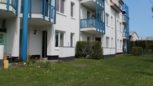 Un immeuble résidentiel à plusieurs étages, doté de balcons, d’un toit plat et d’une pelouse bien entretenue.
