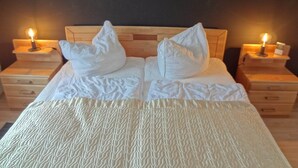 A bed with a wooden headboard, two white pillows, and two bedside tables with lamps. - Helle Wohnung im Ostseebad (Boltenhagen)