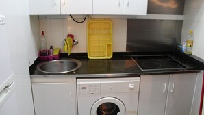 A compact kitchen with a built-in washer and dryer, a sink, and a stove.