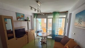 Un ambiente compatto con angolo cottura, zona pranzo e divano.