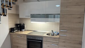 Una cocina moderna con horno empotrado, un lavaplatos y una cafetera.