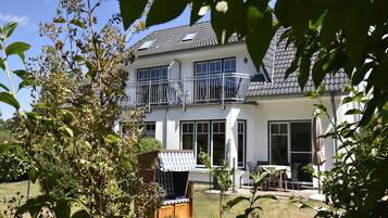 Ein zweistöckiges Haus mit Balkon, einer überdachten Außenveranda und einem Rasen.