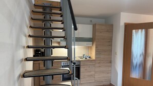 Una cocina moderna con una escalera integrada, armarios de madera y un lavamanos de acero inoxidable.