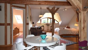 Un dormitorio acogedor en el ático con techo inclinado, un comedor con una mesa redonda y sillas, y vistas al exterior.