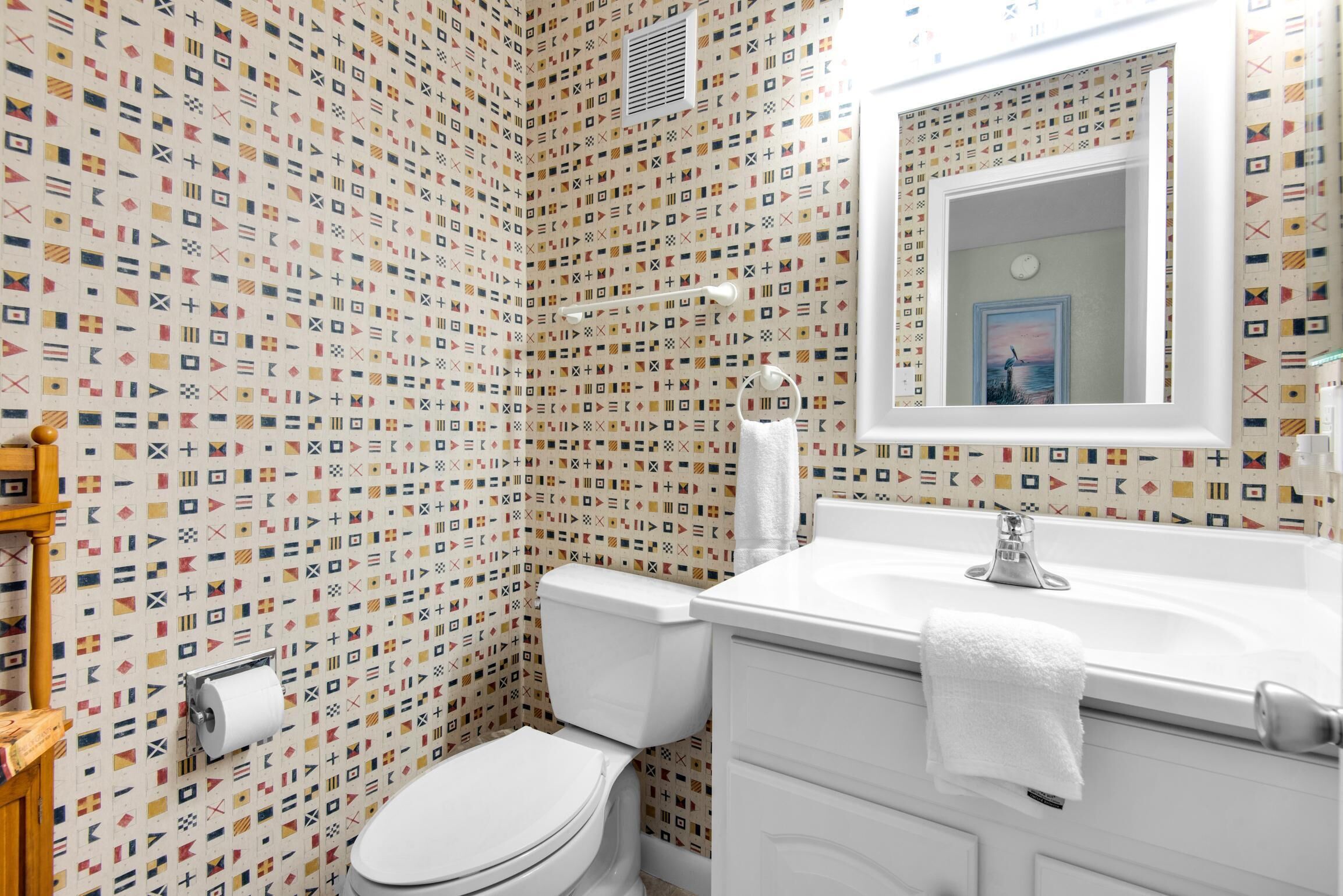 Ein Badezimmer mit Wandmuster, Toilette, Waschbecken und Spiegel.