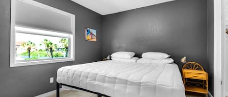 Una camera da letto con un letto, una finestra, un comodino e un quadro.