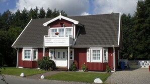 A two-story house with a balcony, a front porch, and a garage. - Moderne Ferienwohnung im Schwedenhaus (Wittenbeck)