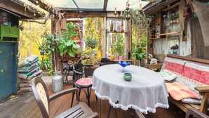 A cozy patio with a table and chairs, surrounded by potted plants and a variety of items on shelves. - Ferienhaus in Wismar mit eigener Terrasse (Wismar)