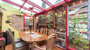 A cozy room with a wooden table and wicker chairs, a glass display case with vintage cars, and a red-framed window. - Ferienhaus in Wismar mit eigener Terrasse (Wismar)