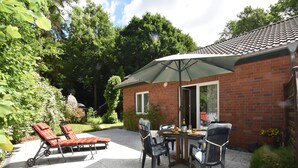 A patio with a table, chairs, and a grill. - Ferienhaus in Damshagen mit Sauna (Klütz)