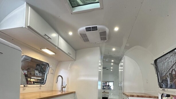 Une cuisine de taille réduite avec des meubles blancs, un four à micro-ondes et un plan de travail en bois.