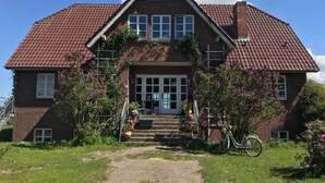 A two-story house with a red-tiled roof, a front porch with steps, and a bicycle parked outside. - Wohnung in Semlow mit Garten und Terrasse (Semlow)