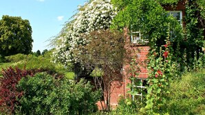 A brick house with a garden full of various plants and flowers. - Wohnung in Semlow mit Garten und Terrasse (Semlow)