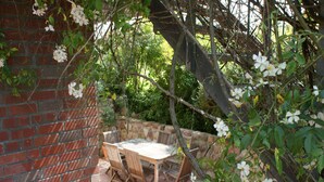An outdoor patio with a brick wall, a wooden table, and chairs. - Wohnung in Semlow mit Garten und Terrasse (Semlow)