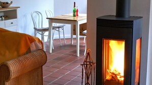 A cozy room with a wicker sofa, a table with chairs, and a wood-burning stove. - Wohnung in Semlow mit Garten und Terrasse (Semlow)