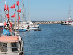 Uma marina com vários barcos atracados, incluindo um barco azul com a inscrição 'FREMAD'.
