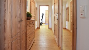 A hallway with wooden doors and a plant on a dresser.