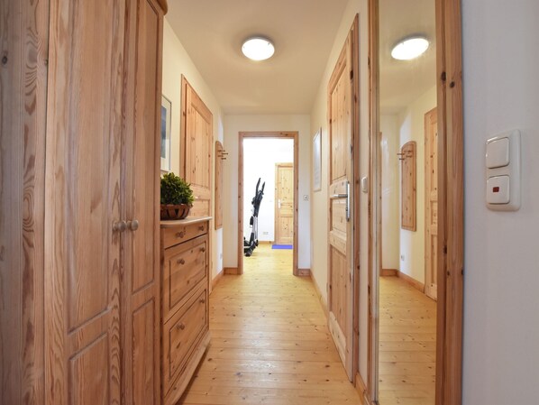 A hallway with wooden doors and a plant on a dresser.