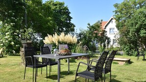 An outdoor patio with a table and chairs, surrounded by lush greenery and trees.