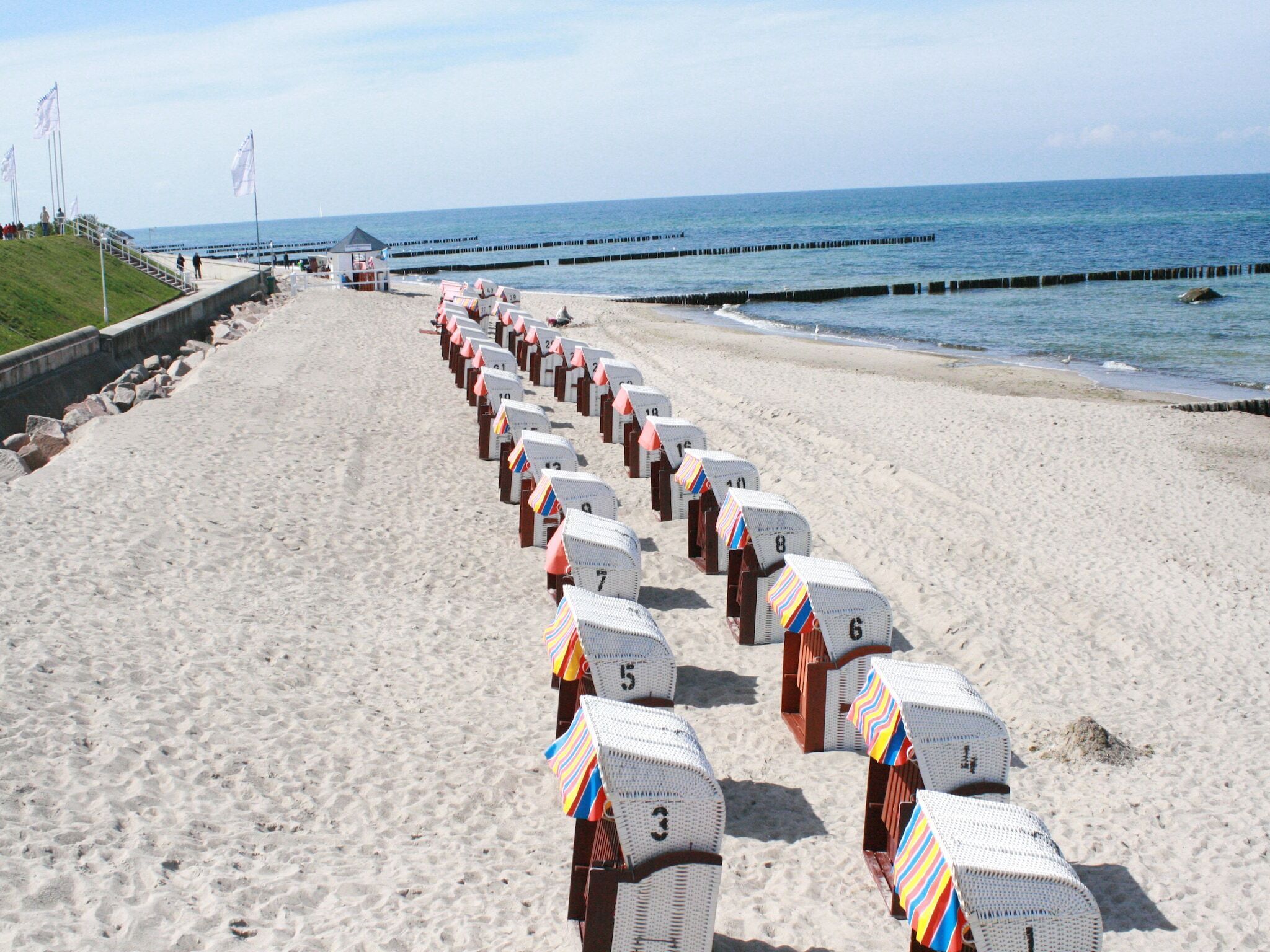 Una playa con hileras de cabañas de playa numeradas a lo largo de la orilla.
