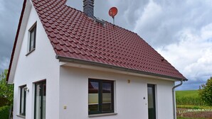 A single-story house with a red-tiled roof, white exterior walls, and a small front porch. - Ferienhaus mit Kamin in Mechelsdorf (Mechelsdorf)