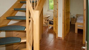 A wooden staircase with blue steps leading to a bedroom with a bed and a nightstand. - Ferienhaus mit Kamin in Mechelsdorf (Mechelsdorf)
